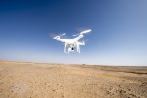 A drone flying over a barren landscape under a clear sky.