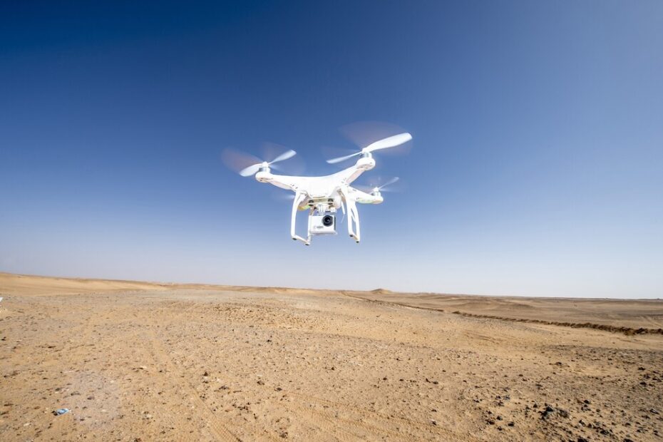 A drone flying over a barren landscape under a clear sky.