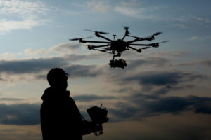 A person operating a drone during sunset, symbolizing the evolution of technology in warfare.